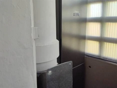 Conduit de vide-ordures en fibres-ciment traversant une loggia
